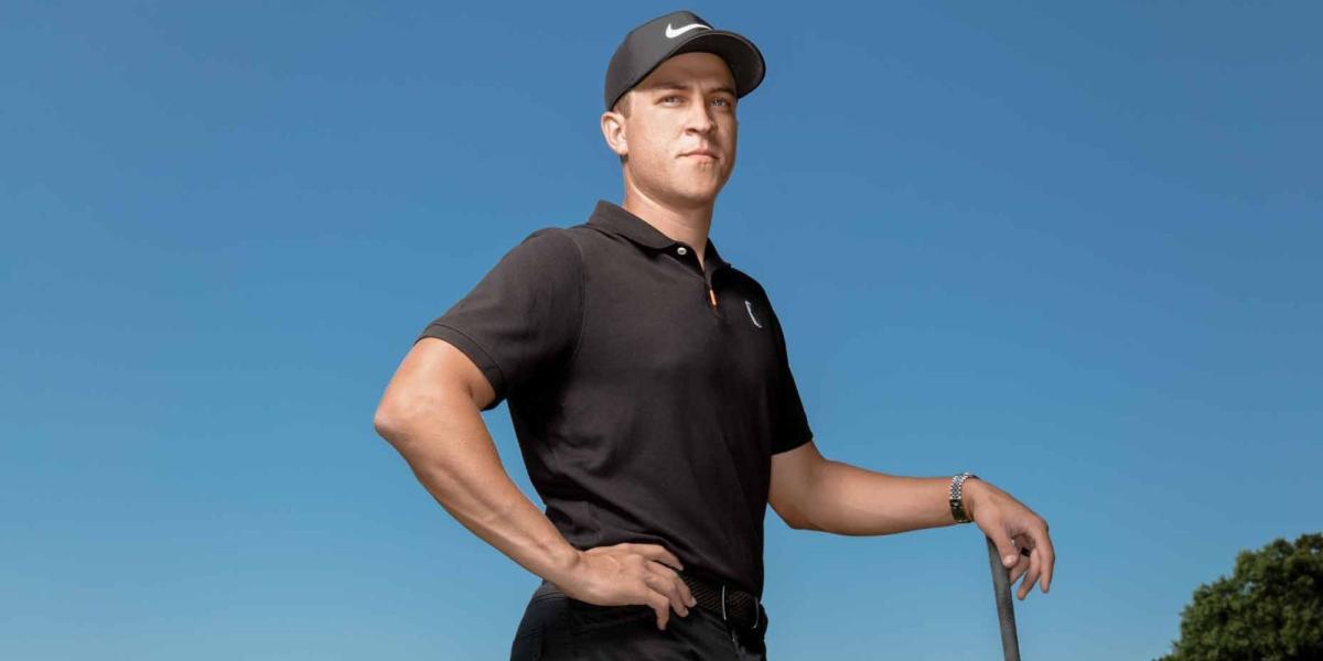 PGA Golfer Cameron Champ posando com uma camisa polo preta e um boné preto da Nike. Ele está apoiado em seu clube de golfe.