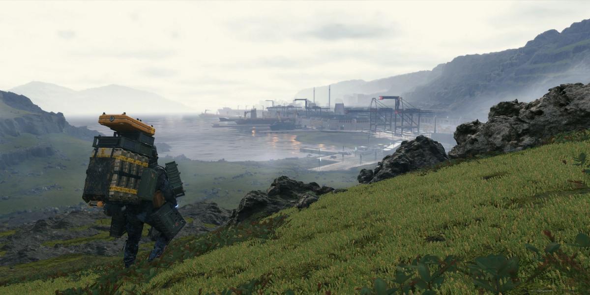 O protagonista fica em uma colina gramada com vista para uma estrutura à distância.