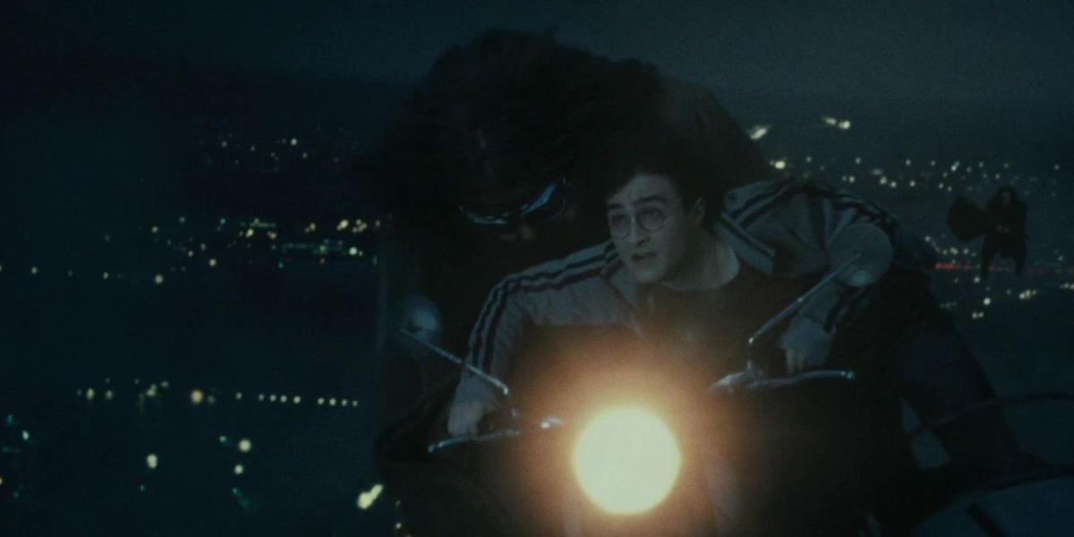 Hagrid e Harry Potter em uma motocicleta voadora sendo perseguidos por um Comensal da Morte