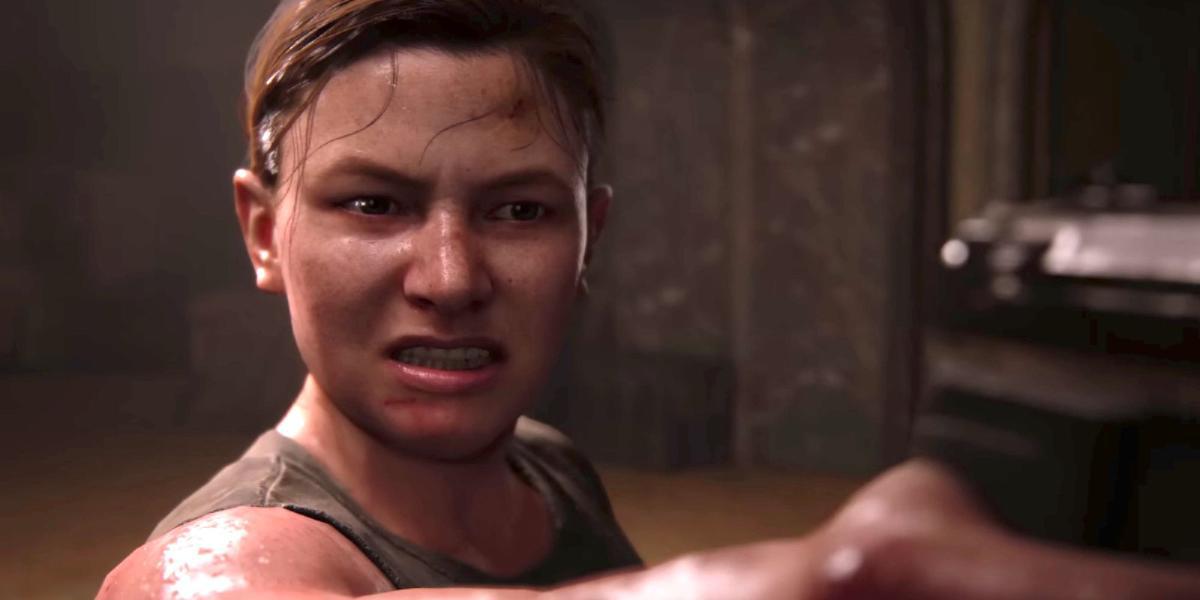 Abby de The Last of Us segurando uma arma com uma careta no rosto.