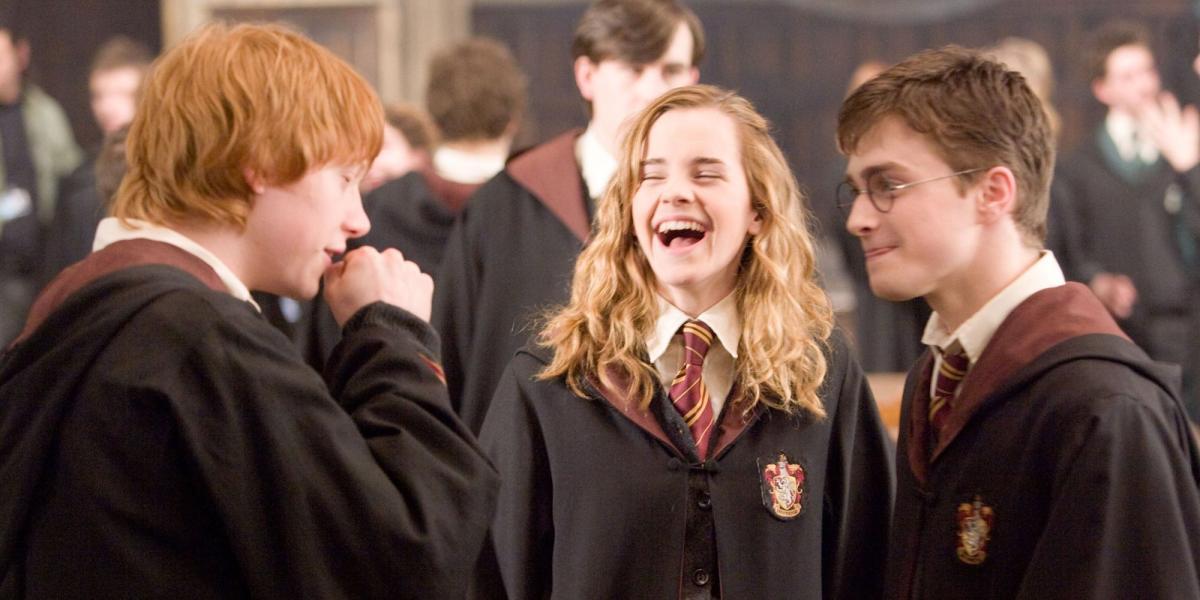 Harry Ron e Hermione rindo no Salão Principal de Hogwarts em Harry Potter
