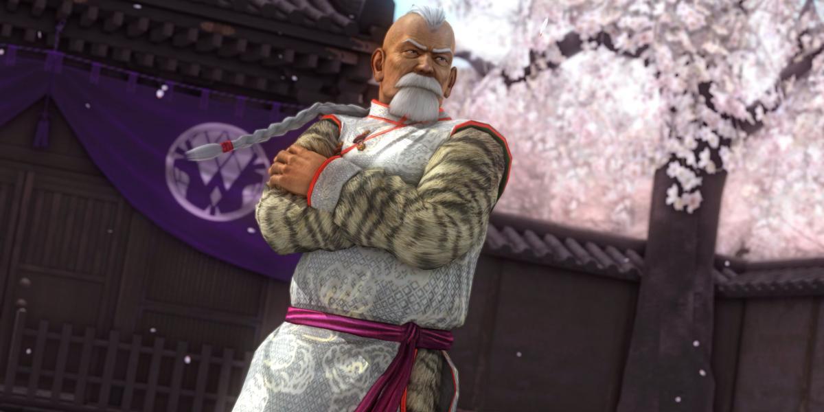 Gen Fu, um homem chinês mais velho no tradicional kimono de luta com flores de cerejeira atrás dele