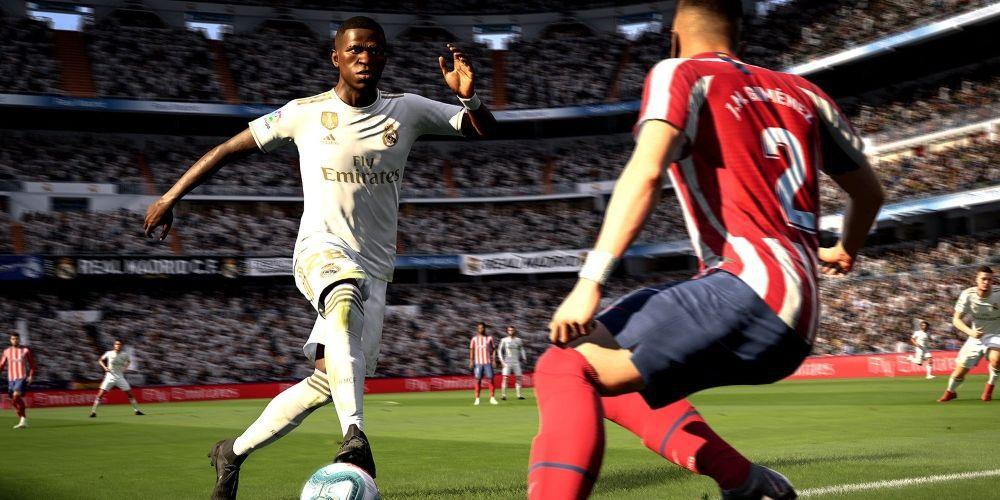 Fifa screenshot jogador de uniforme branco chutando uma bola para longe de um jogador de vermelho e azul-marinho