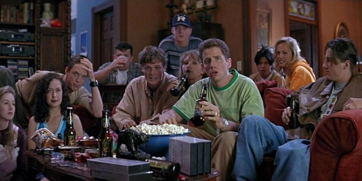 Randy Meeks (Jamie Kennedy) sentado com pessoas em uma festa em Pânico (1996)