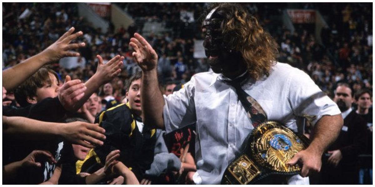 Mankind segurando o WWE Championship cumprimentando membros da multidão