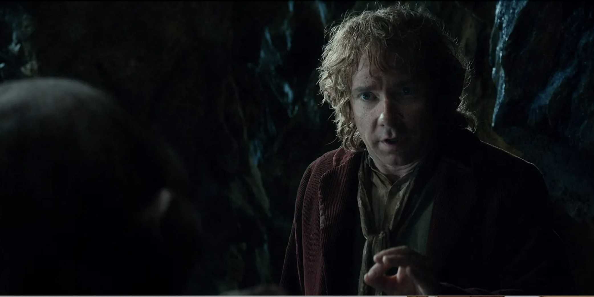 Bilbo looking at Gollum in front of a rock wall from The Hobbit